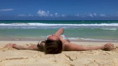 Schöne junge Frau legt sich im Urlaub an einem weißen Sandstrand beim Sonnenbaden