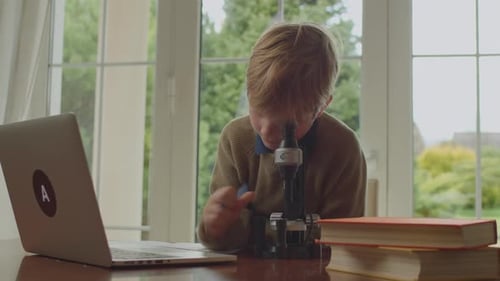 Child Uses Microscope at Table Indoors