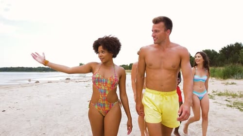 Mixed Race Couple Walking Along Beach with Friends