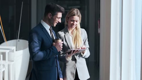 Businessman and woman standing in the street using digital tablet