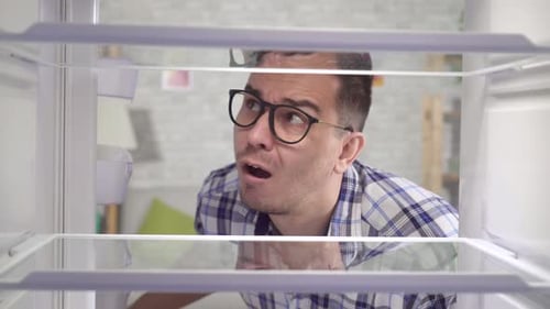 Man Looks into Empty Refrigerator, Thinking About Food