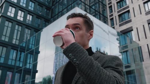 Porträt eines ehrgeizigen Geschäftsmannes, der in der City Center Street steht und Kaffee trinkt. Motiviert