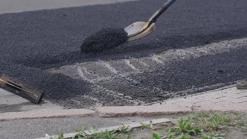 Worker Man Lays Asphalt on a Road Repair Road Paving