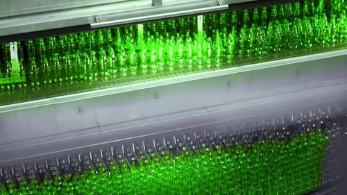 ligne de remplissage de bière dans une brasserie. Bouteilles en verre vert vides se déplaçant sur un tapis roulant dans une file d'attente a