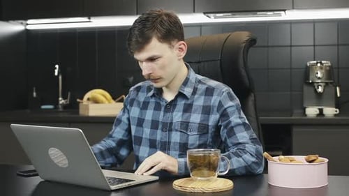 Man Typing on Laptop in Modern Kitchen