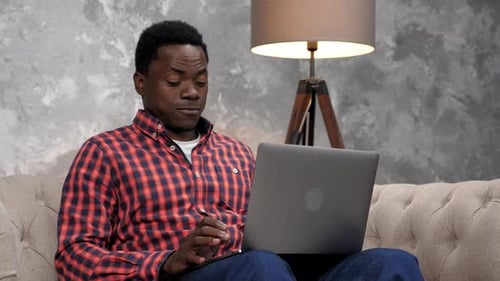 Young Man Typing on Laptop at Home