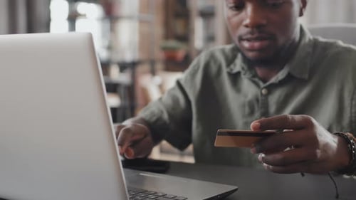 Person Typing on Laptop Holding Credit Card