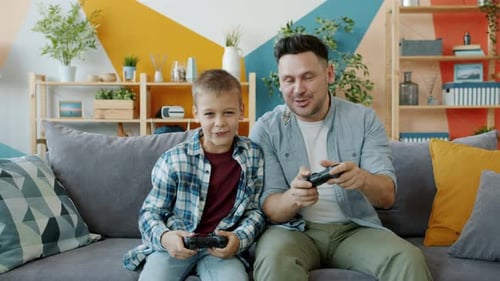 Father and Son Play Video Games on Couch