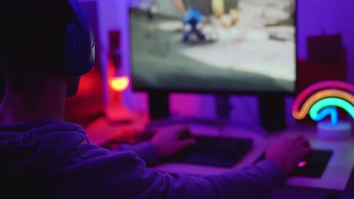 Person Playing Video Game in Neon Lit Room