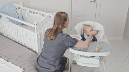 Adult Feeds Food to Baby in Highchair at Home