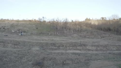 Dirt Bike Rider Jumps on Rural Hillside
