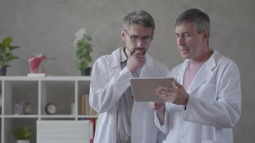 Two Male Doctors Checking Information on the Tablet, Discussing. Concept of Medicine, Technology