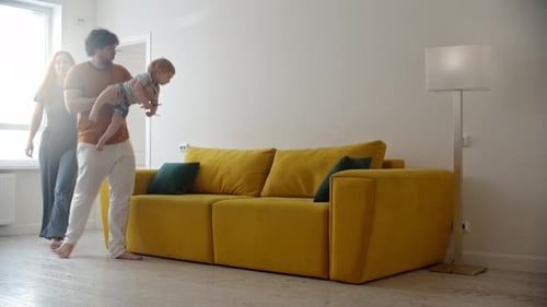 El padre mece al niño en sus brazos y entra en la habitación con su esposa y la familia se sienta en el