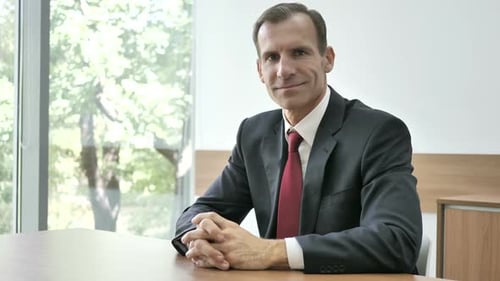 Man Smiles In A Boardroom Wearing A Suit