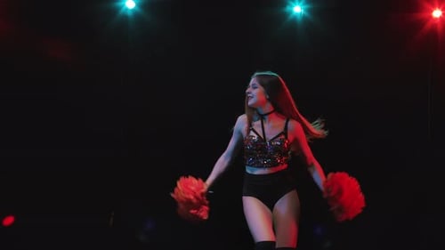 Energetic Woman Dancing with Pom Poms Under Lights