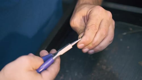 Juwelier verbindet Ringe aus Goldkette am Tisch in Nahaufnahme