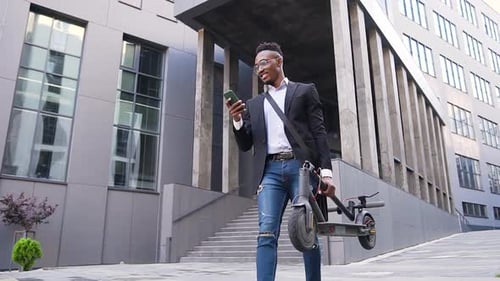 Smiling Man Holding Phone and Electric Scooter