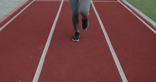 Crop View of Female Person Jogging at Track on Sports Field