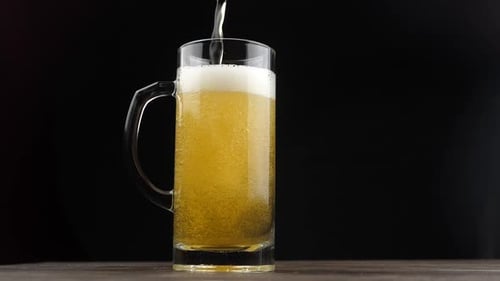 Pouring Draft Beer into Glass Mug on Table