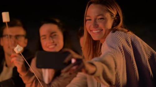 Friends Roast Marshmallows Around Campfire at Night