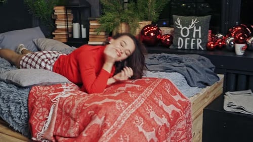 Woman Relaxing on Bed in Christmas Decorated Room