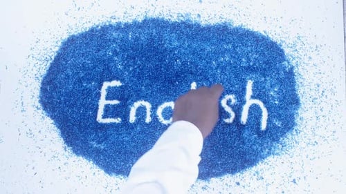 Hand Writes English Word in White Powder