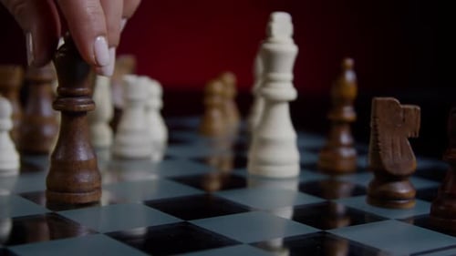 Hand Knocks Over Chess Pieces on Board