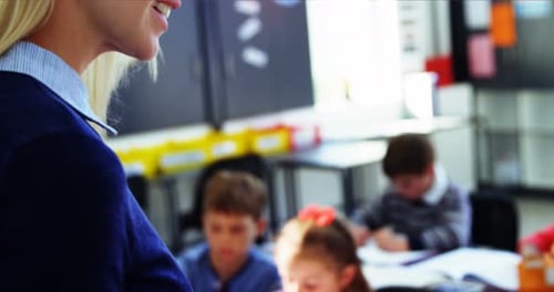 Teacher Helping Students in a Bright Classroom