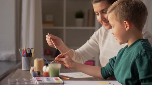 Boy Painting With Woman Indoors