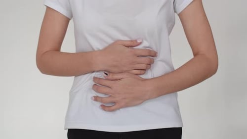 Close-up of Women's Hands Clutching Their Sick Stomach. The Girl Has a Stomach Cramp, She Holds Back