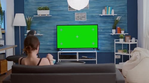 Young Woman Eating Popcorn While Relaxing Watching Movie on Green Screen Television