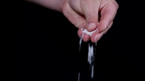 Hand Scatters Salt on a Black Background