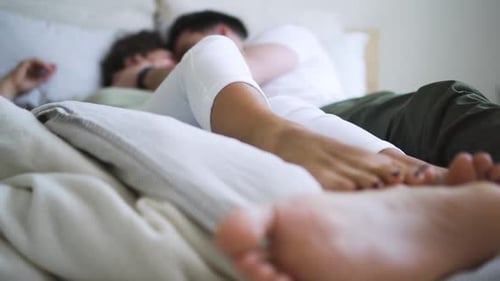 Junges amerikanisches Paar zeigt Liebe und Leidenschaft, während es im White Room auf dem Bett liegt Spbd