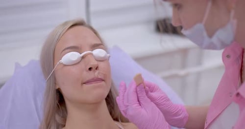 Die Kosmetikerin trägt der Frau ein Gel zur Laser-Haarentfernung auf ihre Oberlippe auf. Kosmetische Eingriffe in