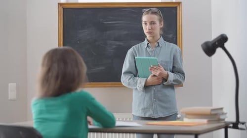 Teacher Explaining Lesson to Student in Classroom