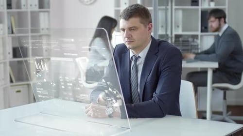 Geschäftsmann mit Handprothese arbeitet am AR-Bildschirm am Schreibtisch