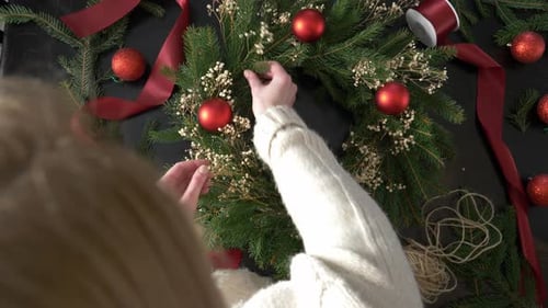 Hands Decorating a Christmas Wreath at Home