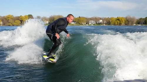 A man wake surfing behind a boat on a lake