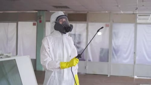 Person in Hazmat Suit Spraying Disinfectant Indoors