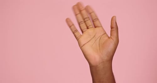 Hand Waving Against Pink Background
