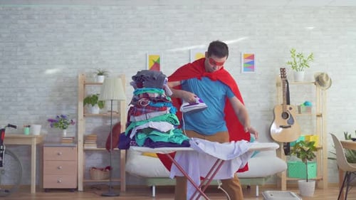 Man Dressed as Superhero Ironing Laundry at Home