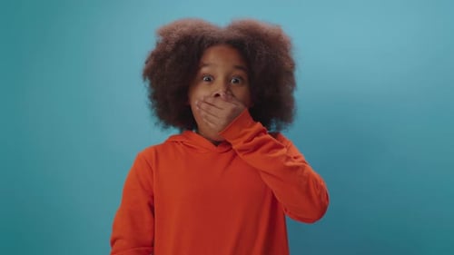 Shocked kid opening mouth and closing it with hand