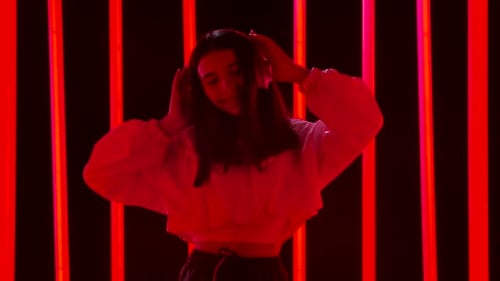 Stylish Woman Dances with Headphones in Neon Lights