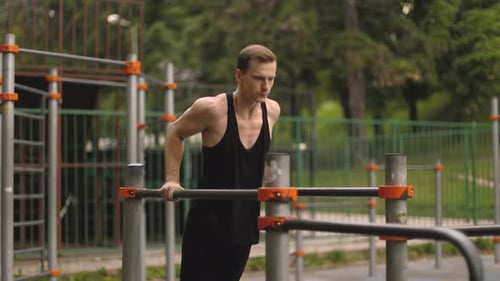 Fit Man Doing Triceps Dips on Parallel Bars at Park Exercising Outdoors