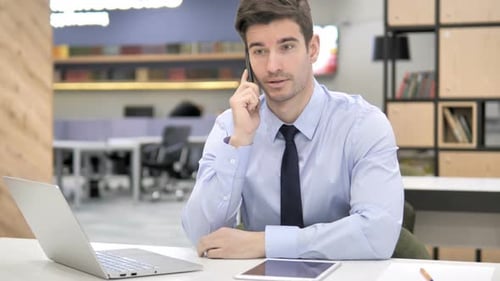 Man Talking on Phone in Modern Office Setting