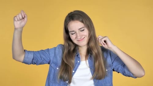 Young Woman Dancing Happily Against Yellow Background