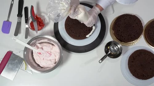 Vista superior del chef con una manga pastelera rellena de crema para delinear la primera capa de un conjunto de pastel