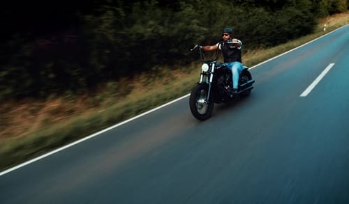 Man Rides Motorcycle Down Country Road