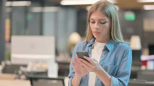 Young Woman Using Smartphone in Modern Office