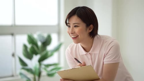 Woman Writing on Clipboard, Smiling and Speaking